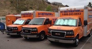 Water Damage Restoration Vans And Trucks At Job Site